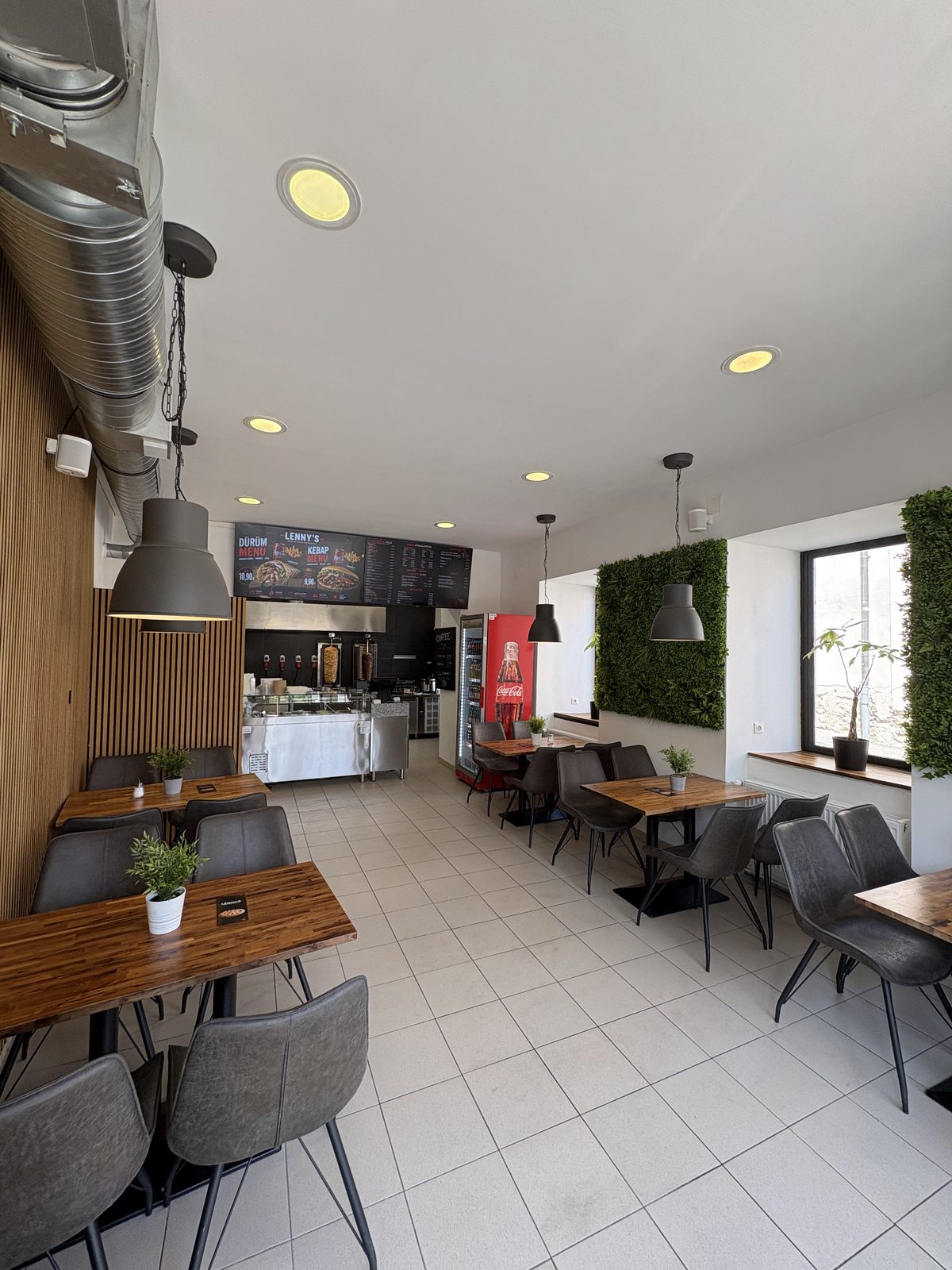 Moderner Gastraum von Lenny's mit Holztischen und Mooswand